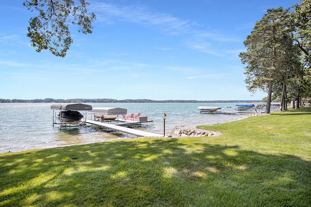 view of dock with a water view and a lawn