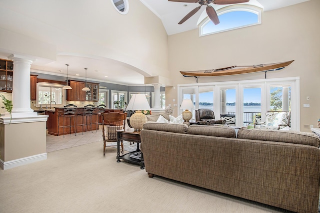 carpeted living room with decorative columns, a water view, and plenty of natural light