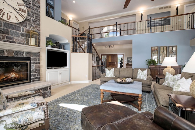 carpeted living room with built in features, ceiling fan, a high ceiling, a fireplace, and ornamental molding