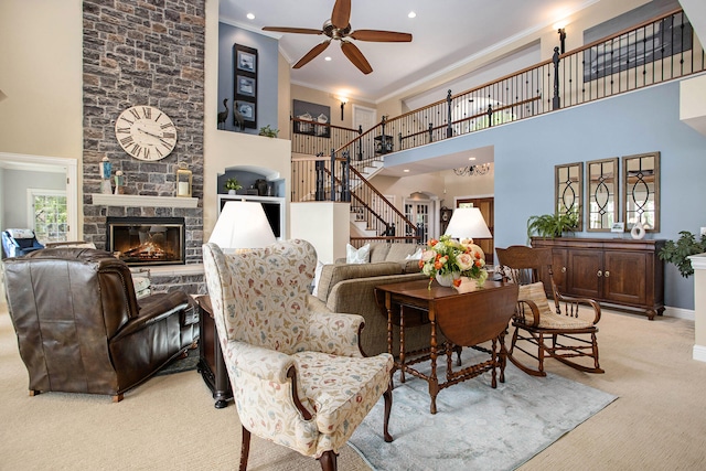 living room with light colored carpet, ornamental molding, a towering ceiling, ceiling fan, and a fireplace