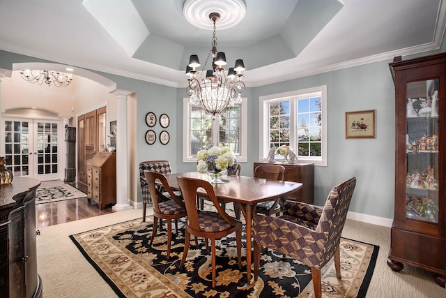 dining area featuring ornate columns, a raised ceiling, crown molding, an inviting chandelier, and french doors