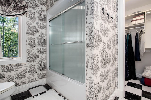 bathroom featuring enclosed tub / shower combo and toilet