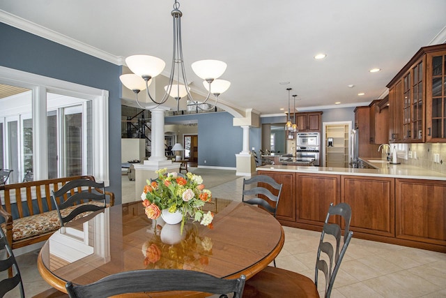 dining room featuring sink, light tile patterned floors, ornamental molding, and ornate columns