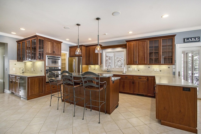 kitchen featuring a kitchen island, decorative light fixtures, sink, a kitchen bar, and stainless steel appliances