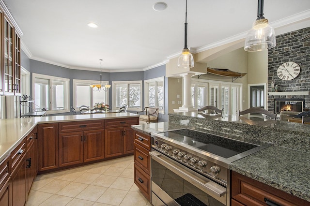 kitchen with light tile patterned flooring, a stone fireplace, decorative light fixtures, high end stainless steel range oven, and crown molding