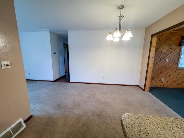 empty room with dark carpet and an inviting chandelier