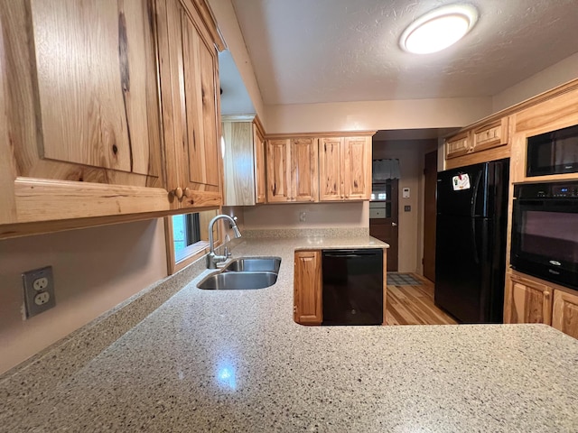 kitchen with light stone counters, sink, black appliances, and a textured ceiling