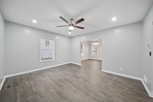 spare room featuring dark hardwood / wood-style flooring, ceiling fan, and a healthy amount of sunlight