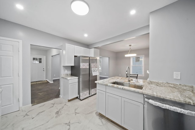 kitchen with sink, hanging light fixtures, light stone counters, white cabinets, and appliances with stainless steel finishes