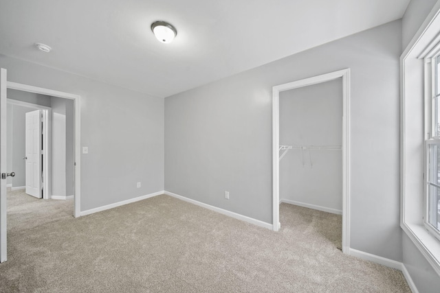 unfurnished bedroom with light colored carpet, a spacious closet, and a closet