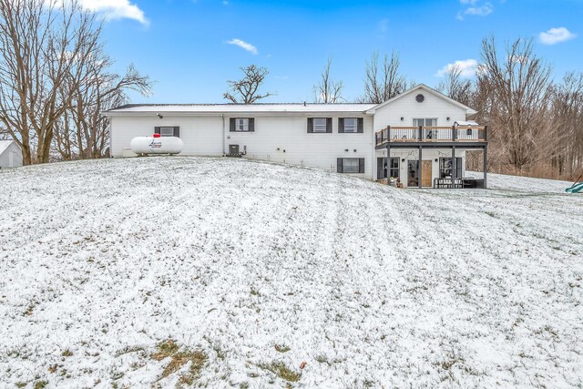 snow covered house with cooling unit and a wooden deck