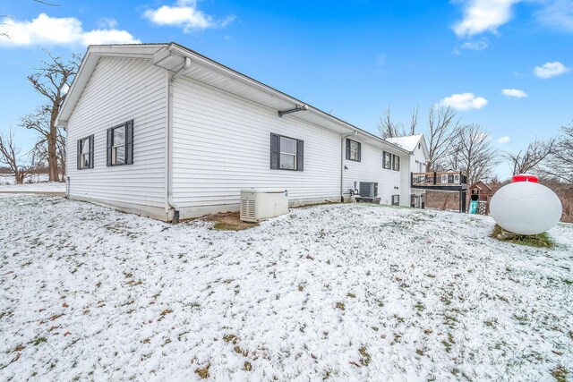 snow covered back of property featuring central air condition unit