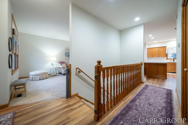 corridor with sink, light hardwood / wood-style floors, and lofted ceiling