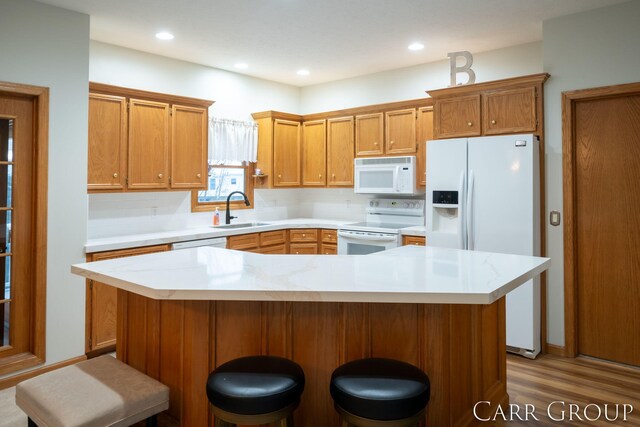 kitchen featuring tasteful backsplash, a breakfast bar, sink, and white appliances