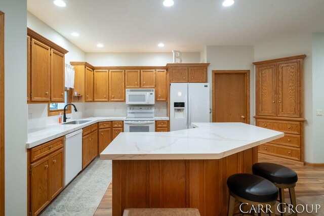 kitchen featuring sink, a kitchen breakfast bar, white appliances, decorative backsplash, and a kitchen island