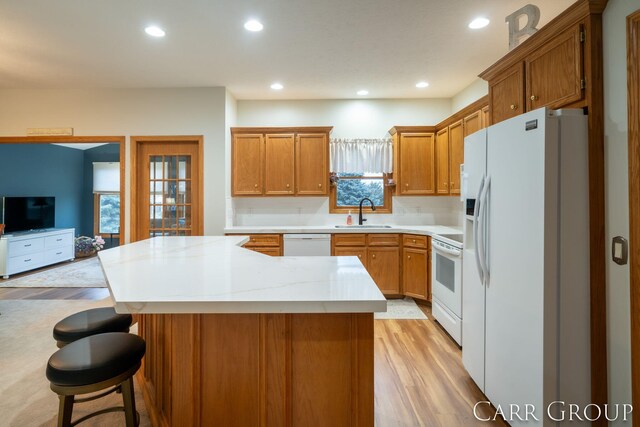 kitchen featuring a kitchen breakfast bar, sink, a healthy amount of sunlight, and white appliances