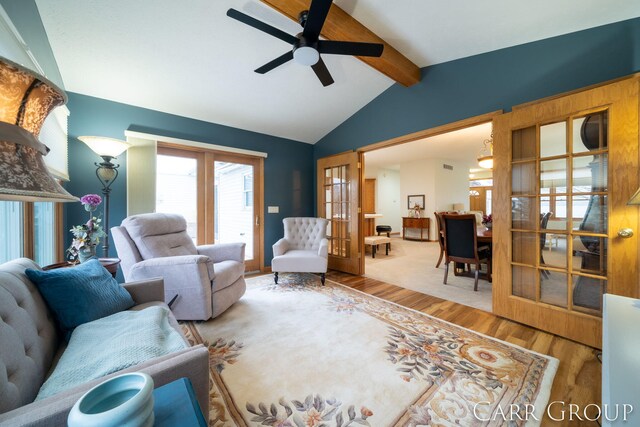 living room with french doors, vaulted ceiling with beams, ceiling fan, and wood-type flooring