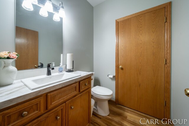 bathroom with hardwood / wood-style flooring, vanity, and toilet