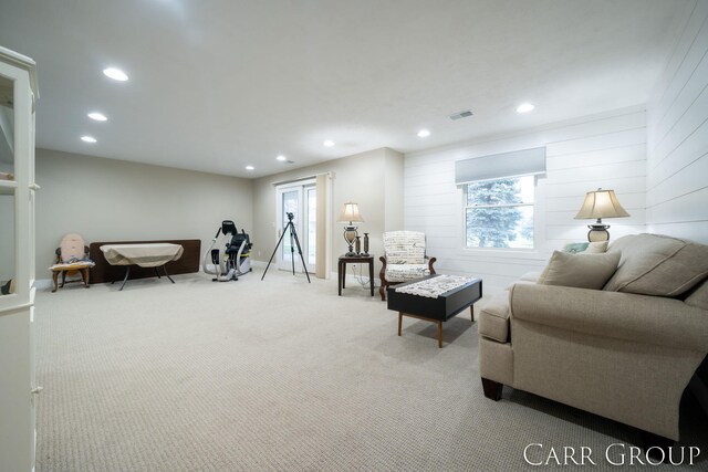 carpeted living room with wooden walls