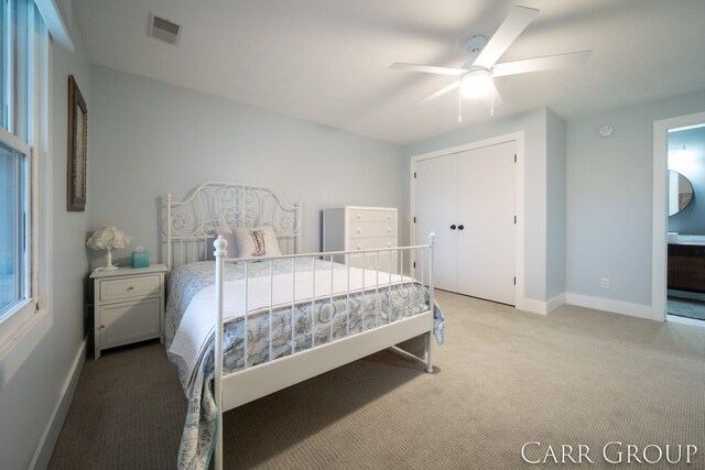 carpeted bedroom featuring a closet, ensuite bathroom, and ceiling fan