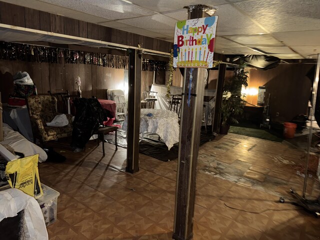 basement with wooden walls, a drop ceiling, and parquet flooring