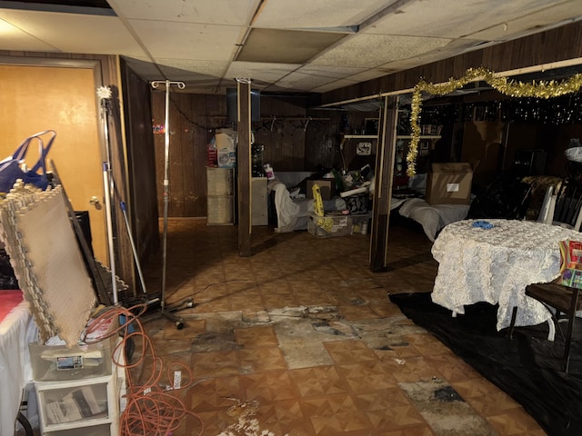 basement with a paneled ceiling and wooden walls