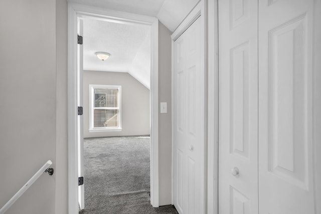 hall with a textured ceiling, carpet, and lofted ceiling