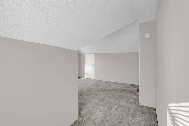 carpeted empty room with lofted ceiling and a textured ceiling