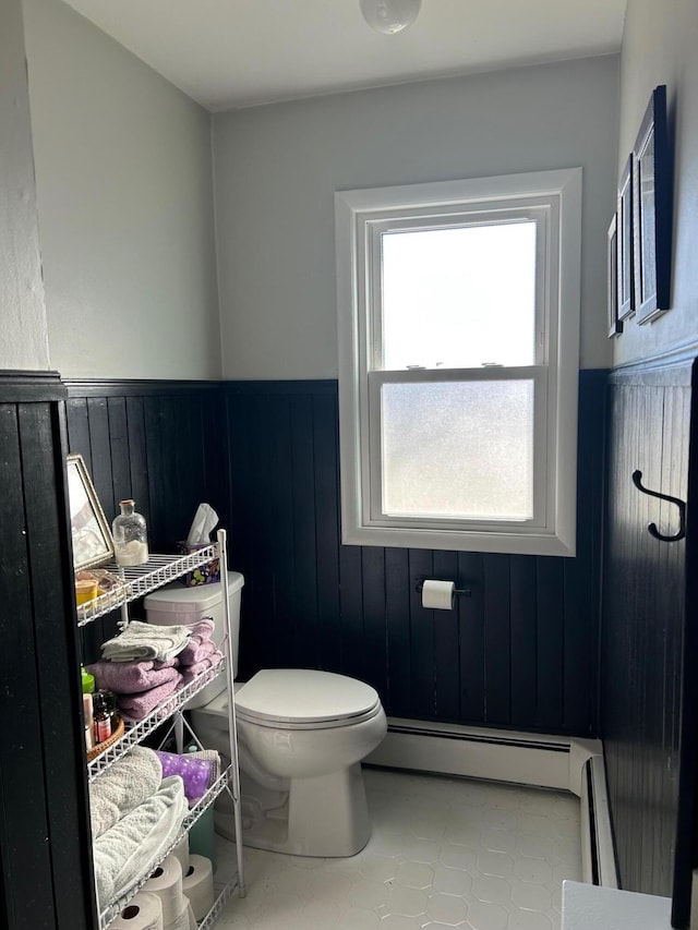 bathroom featuring a baseboard radiator, toilet, wooden walls, and tile patterned flooring