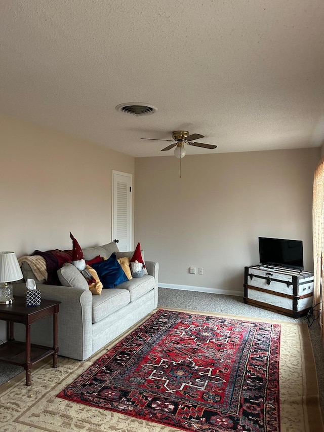 living room with a textured ceiling and ceiling fan