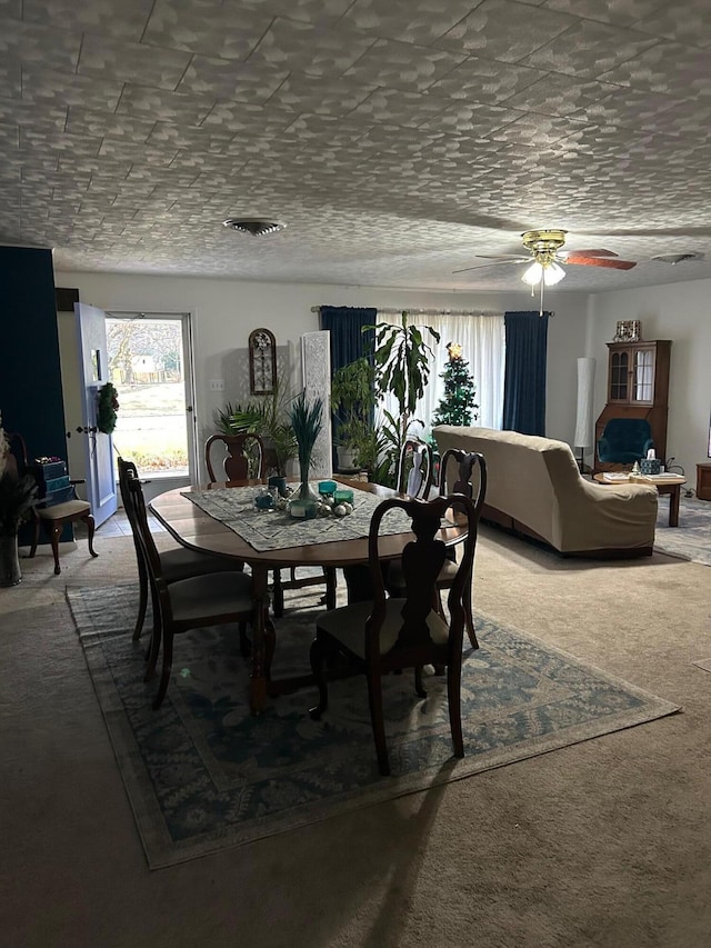 carpeted dining space with ceiling fan and a textured ceiling