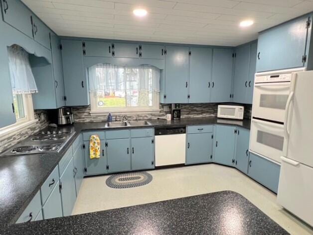 kitchen with blue cabinetry, white appliances, and sink