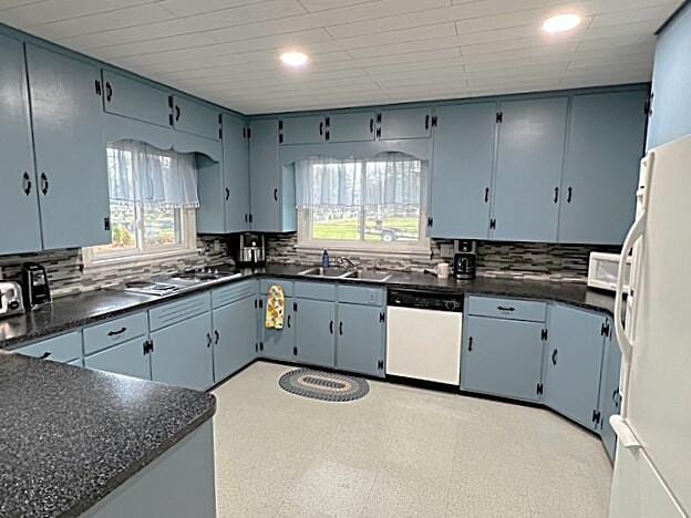 kitchen featuring sink, white appliances, and blue cabinetry