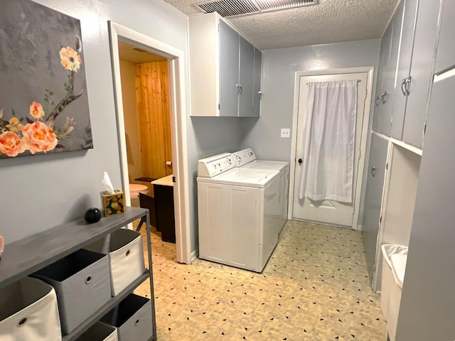 laundry room featuring a textured ceiling, cabinets, and washing machine and clothes dryer