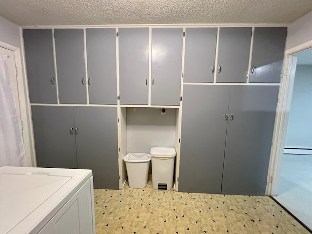 laundry area with cabinets, baseboard heating, a textured ceiling, and washer / clothes dryer