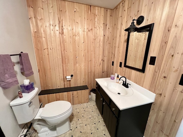 bathroom featuring toilet, vanity, and wood walls