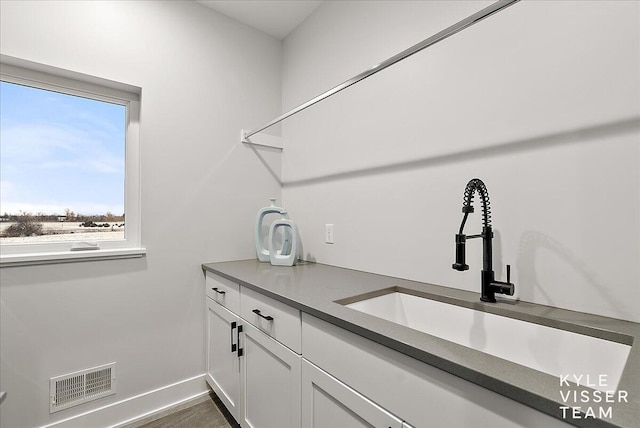 bar with white cabinets, dark hardwood / wood-style floors, and sink