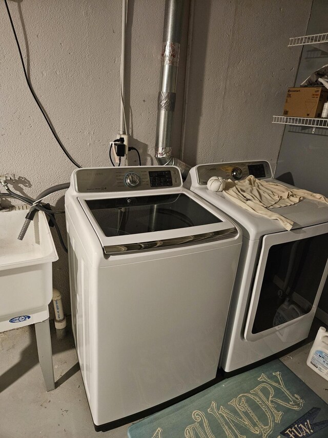 laundry room with washer and dryer, laundry area, a textured wall, and a sink