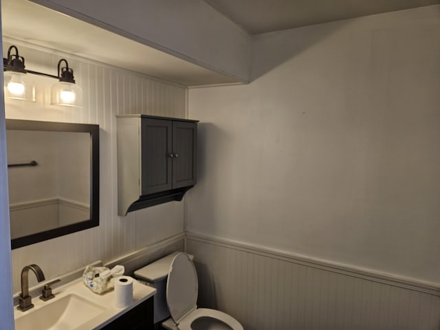 half bathroom featuring wainscoting, vanity, and toilet