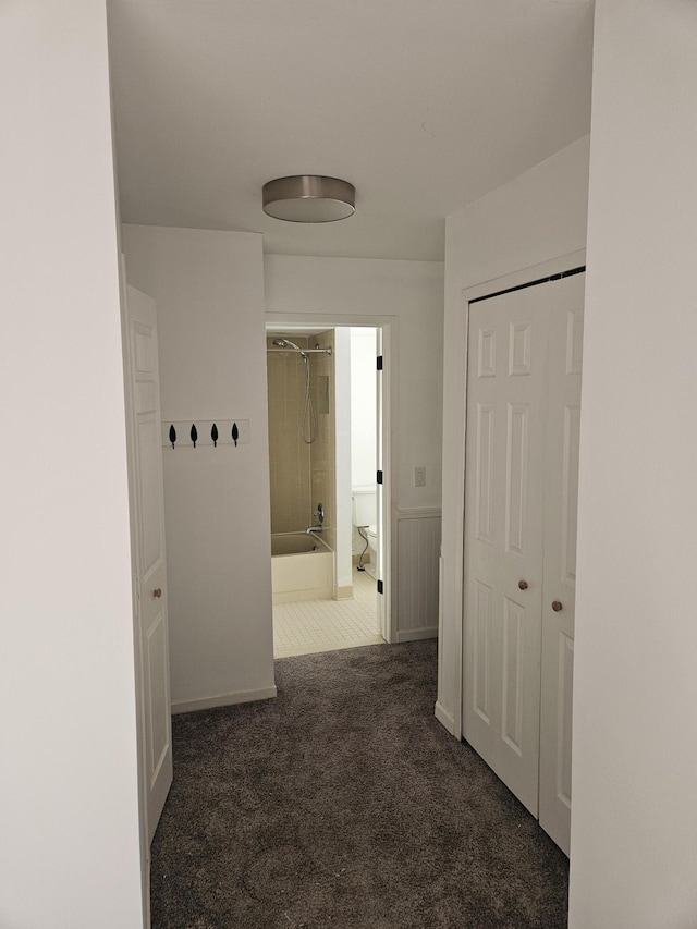 corridor with dark colored carpet and wainscoting