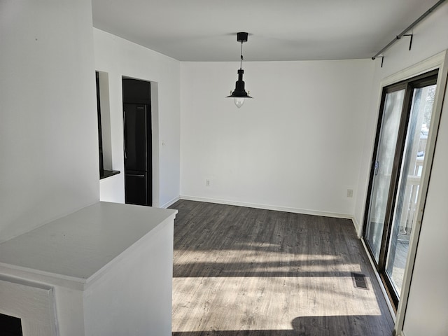 unfurnished dining area featuring baseboards, visible vents, and dark wood finished floors