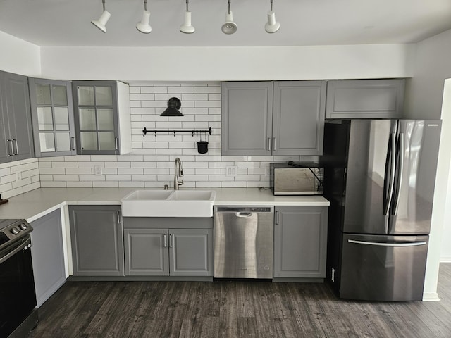 kitchen with glass insert cabinets, appliances with stainless steel finishes, light countertops, gray cabinetry, and a sink