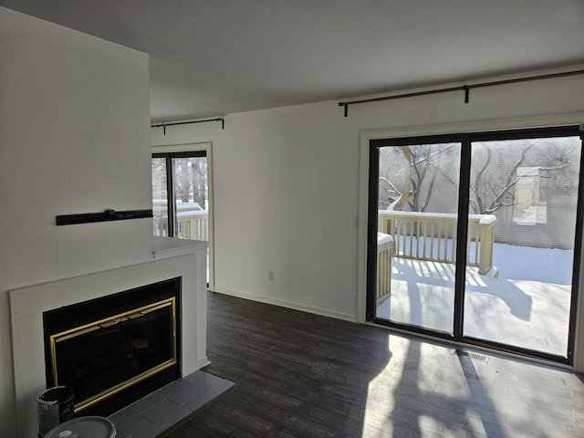 unfurnished living room with a fireplace with flush hearth, dark wood finished floors, and baseboards