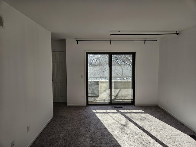 empty room with baseboards and dark colored carpet