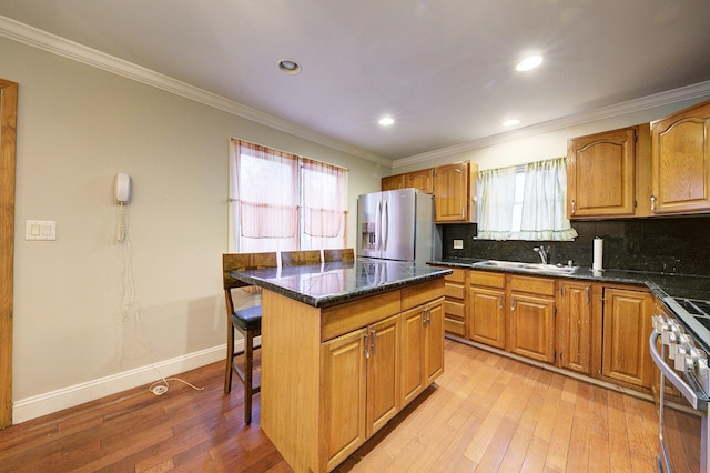 kitchen with a center island, sink, stainless steel appliances, plenty of natural light, and a breakfast bar