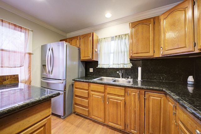 kitchen with decorative backsplash, stainless steel fridge, light wood-type flooring, ornamental molding, and sink