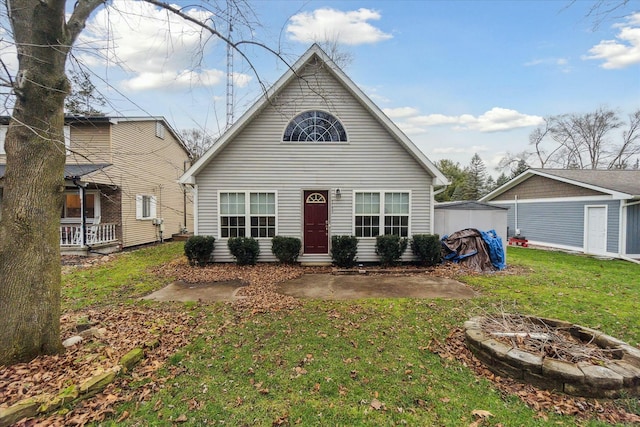 bungalow-style home featuring a shed, a fire pit, a front lawn, and an outdoor structure