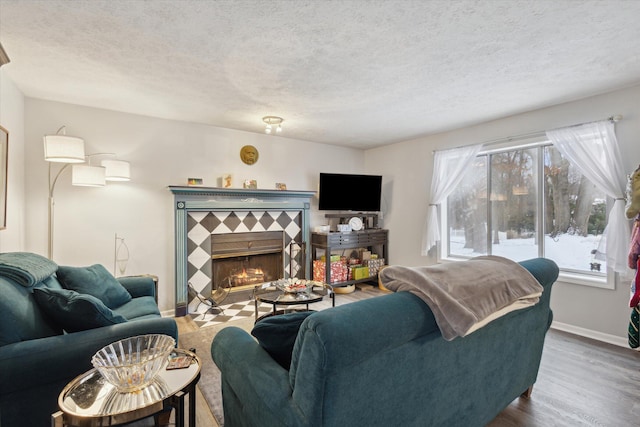 living room featuring hardwood / wood-style floors, a textured ceiling, and a tiled fireplace