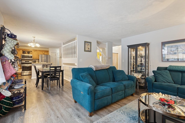 living room with light hardwood / wood-style floors and a notable chandelier