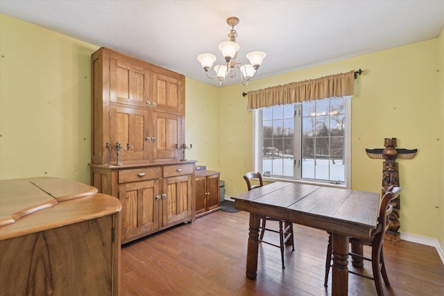 dining area with hardwood / wood-style floors and an inviting chandelier